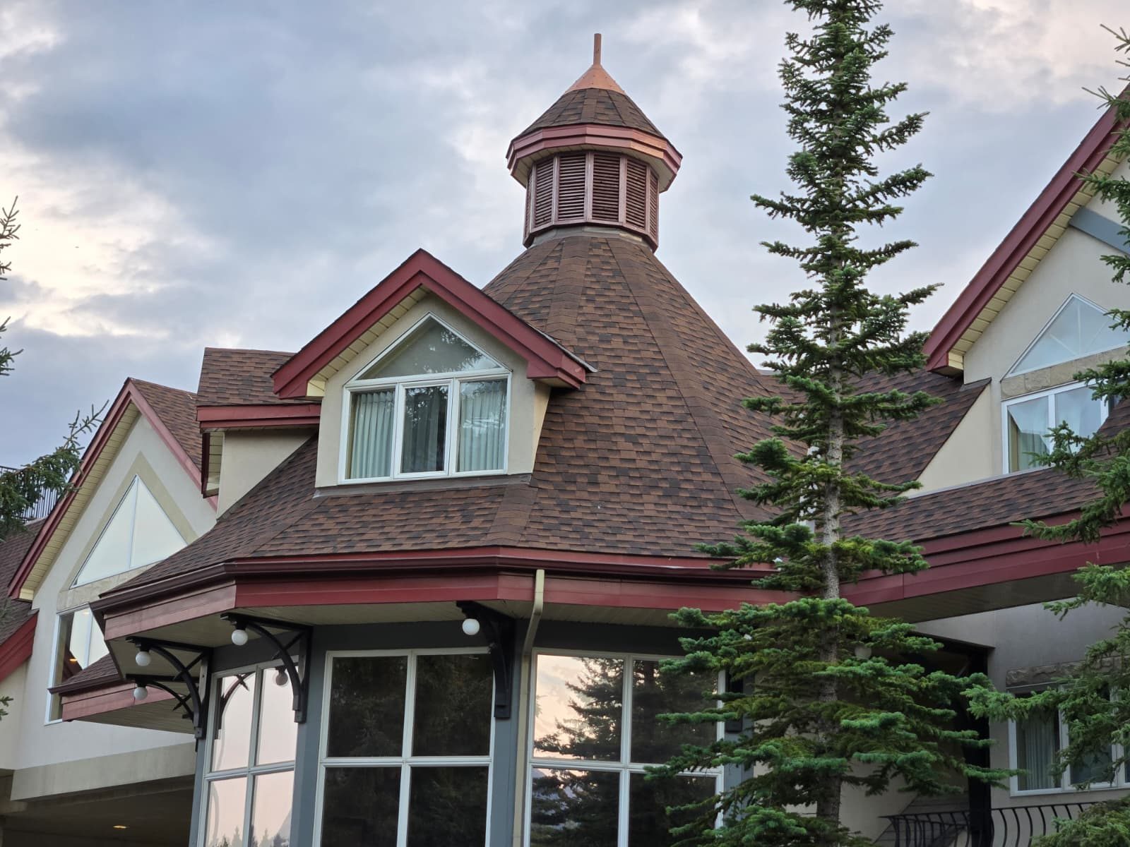 Shingled cupola and dormer roof with red trim on a large building