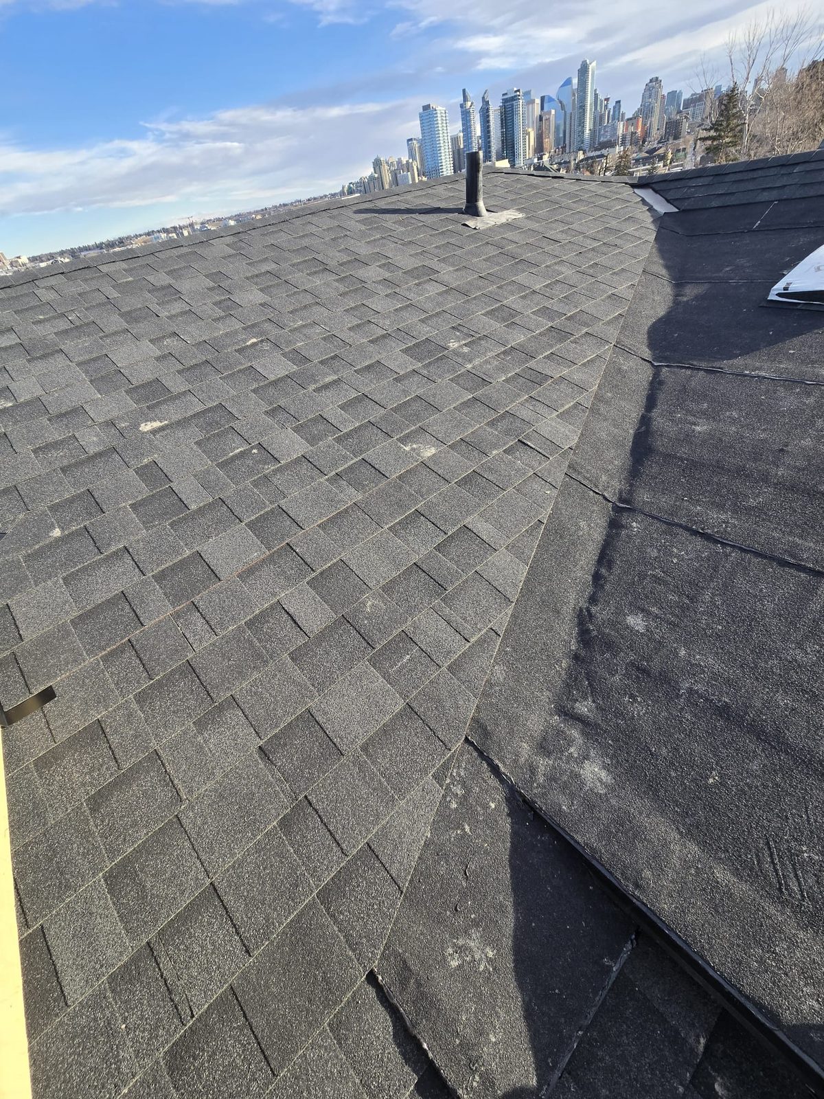 Low-slope black membrane next to a finished shingle roof