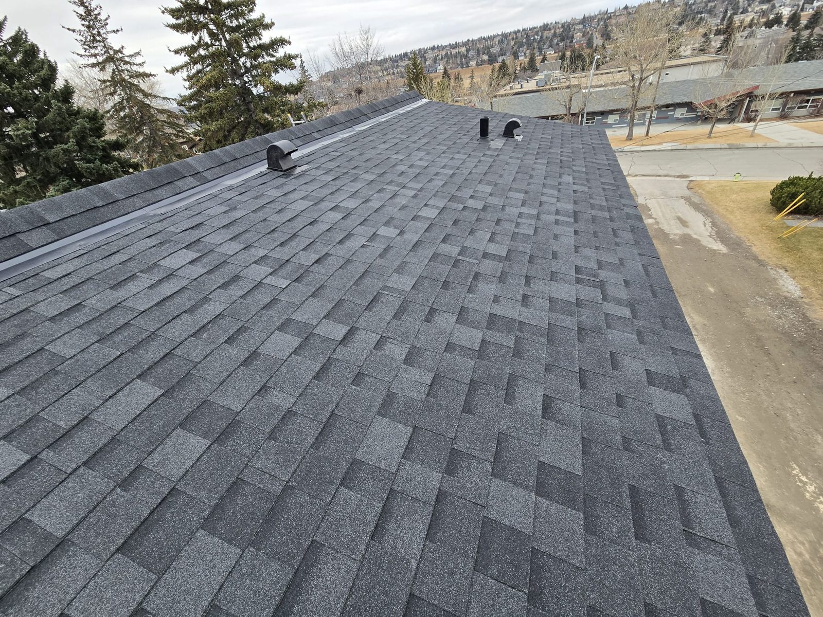 Grey shingle roof with ridge flashing and vents