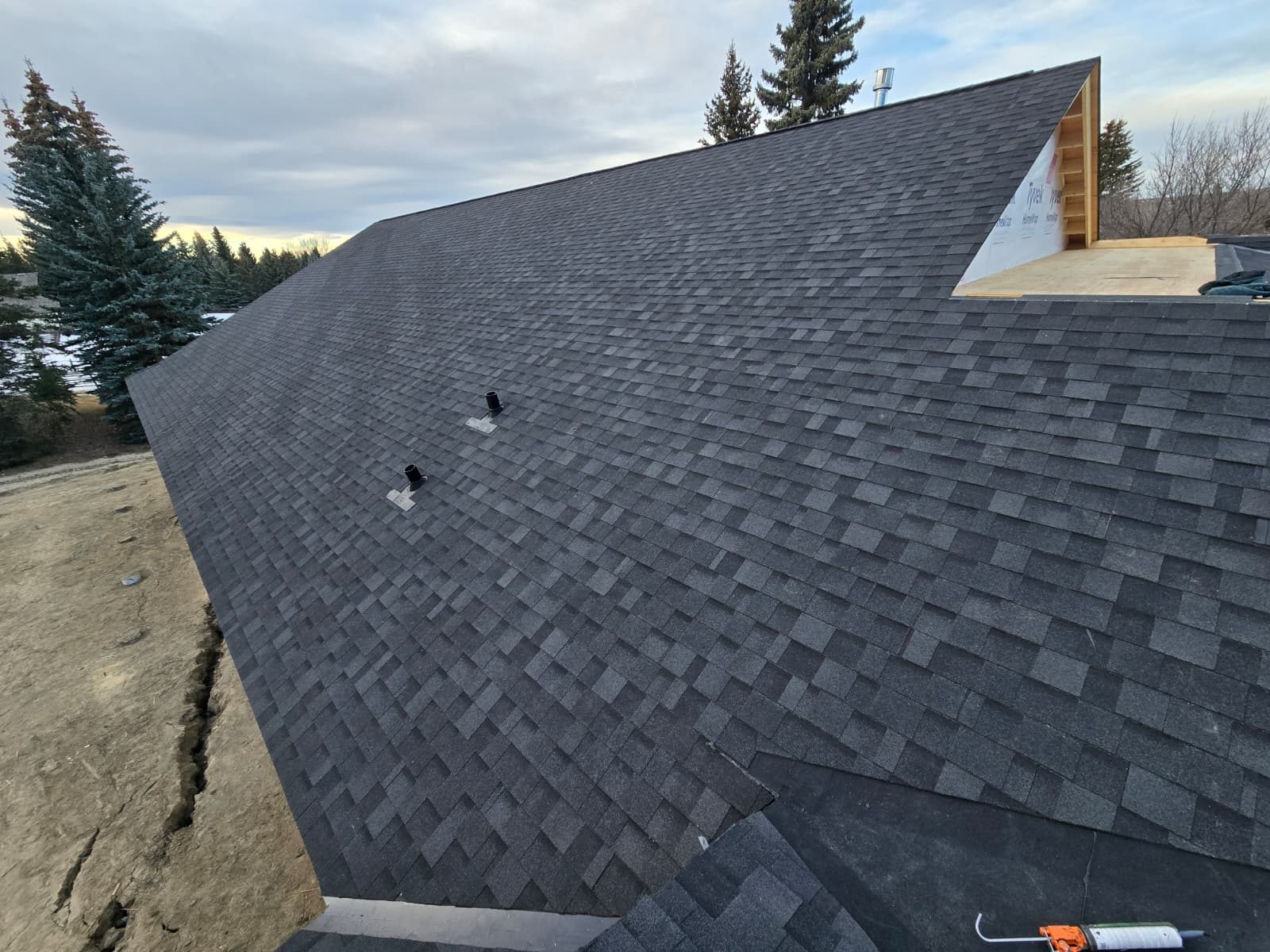 New build roof with black vent pipes and house wrap on the gable