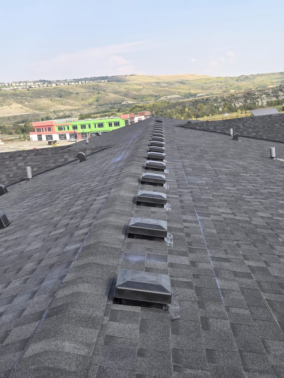 Long roof ridge with a row of ridge vents on dark shingles
