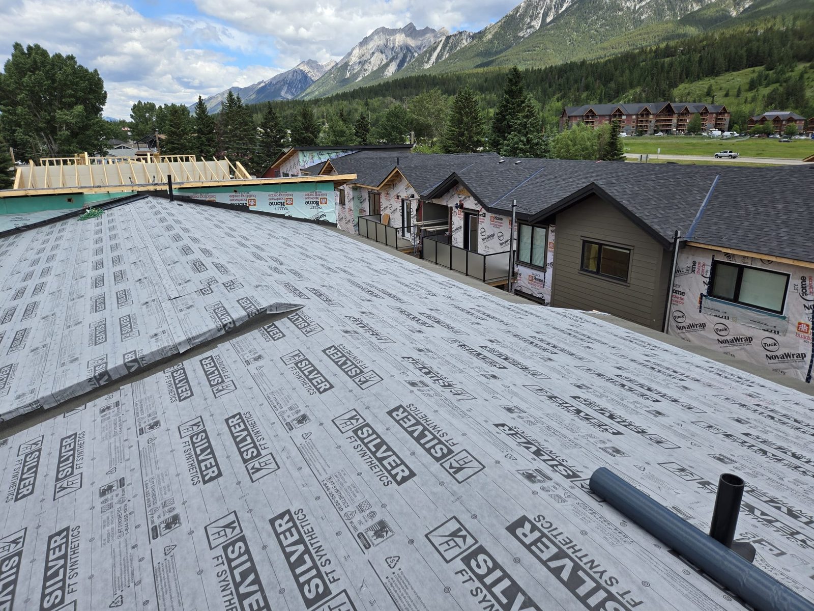 Roof covered in grey synthetic underlayment with mountains in the background